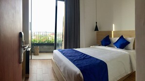 Een hotelkamer met een bed, balkon en uitzicht op de omgeving.