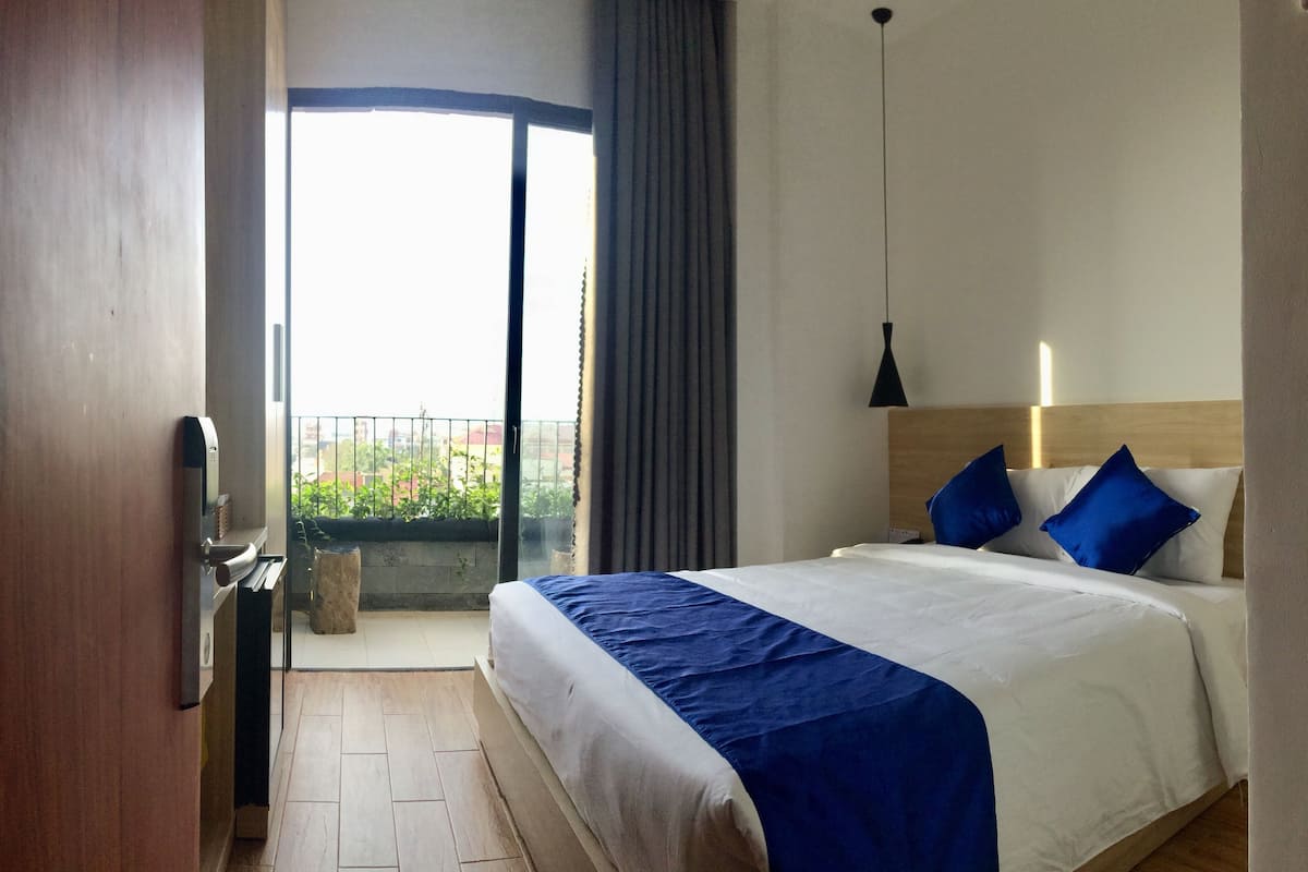 A hotel room with a bed, a balcony, and a view of the outdoors.