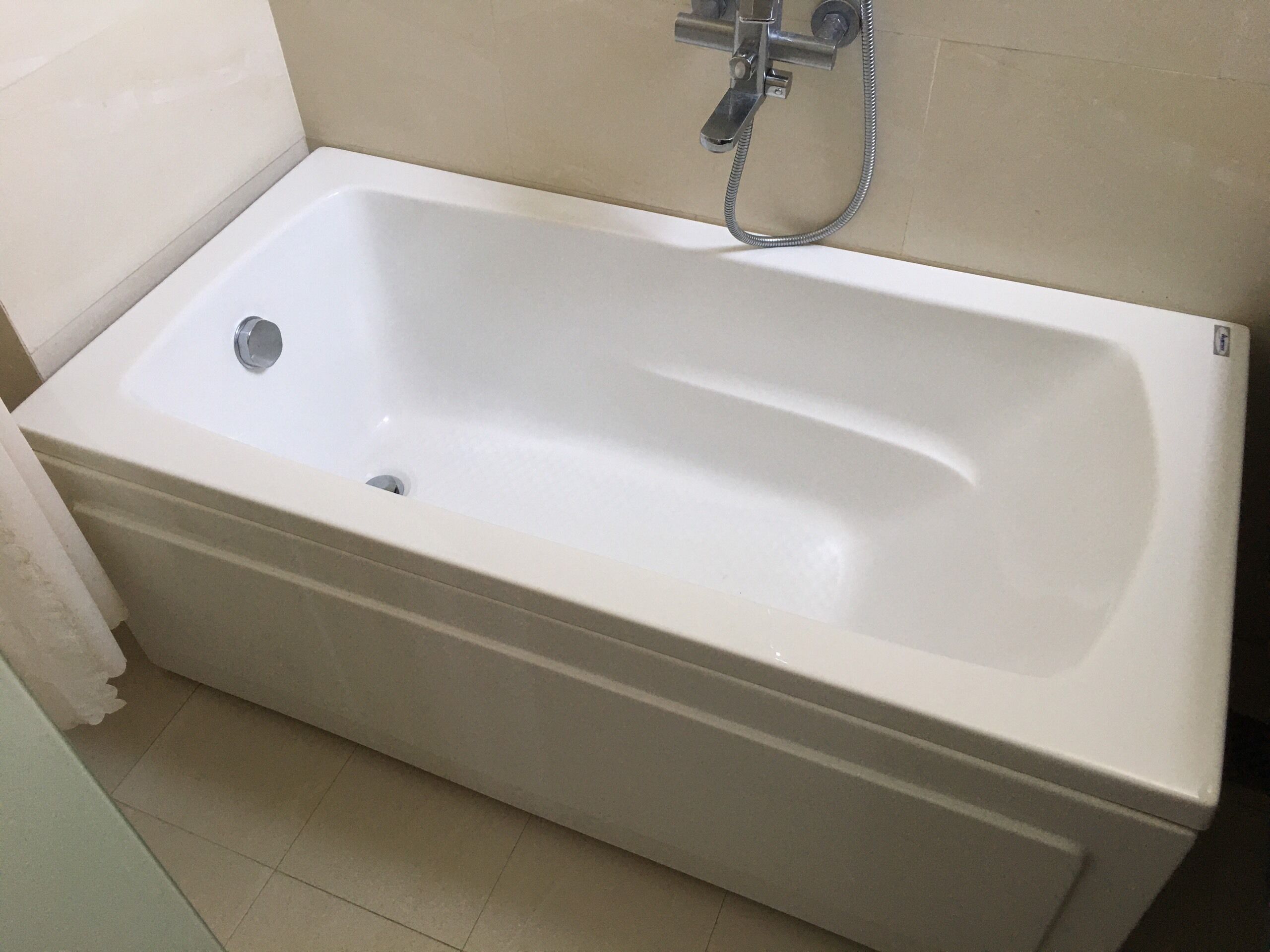 A white bathtub in a bathroom with a shower head and hose.