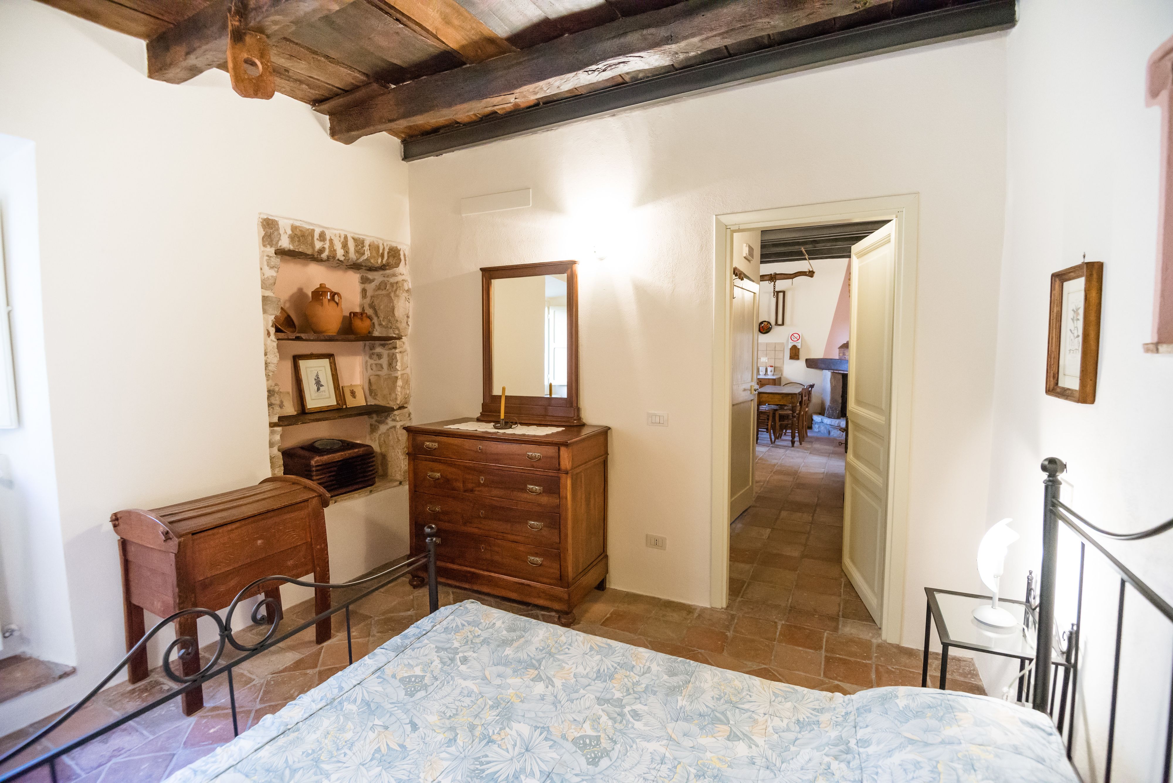 A bedroom with a bed, wooden dresser, and a stone wall shelf.