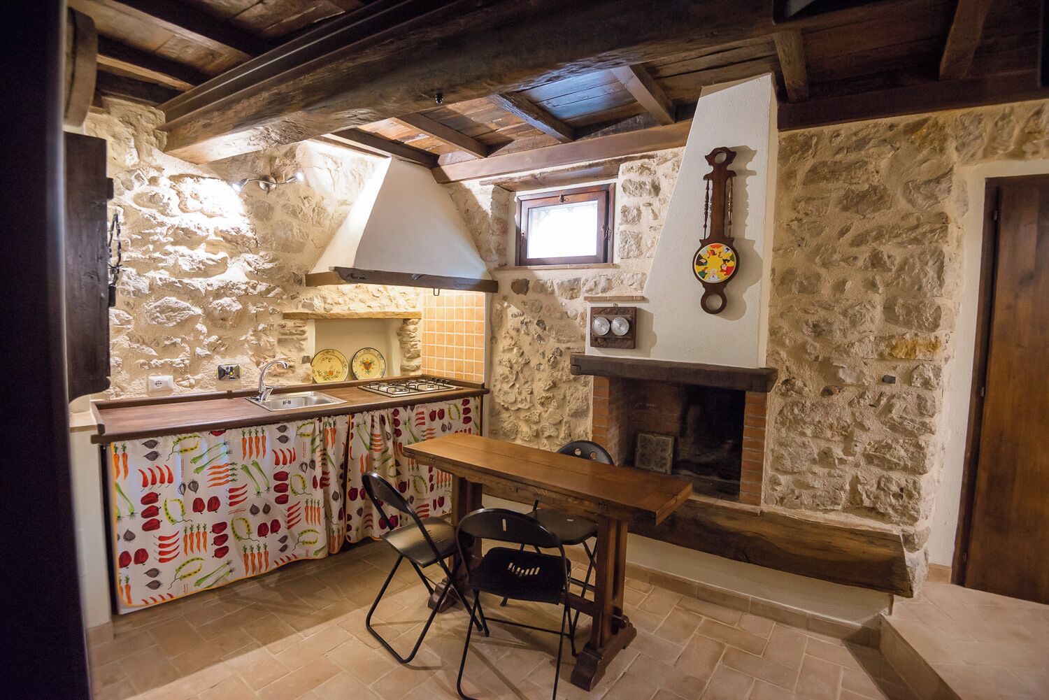 Eine rustikale Küche mit Steinwänden, einem Holztisch und einem Gasherd.