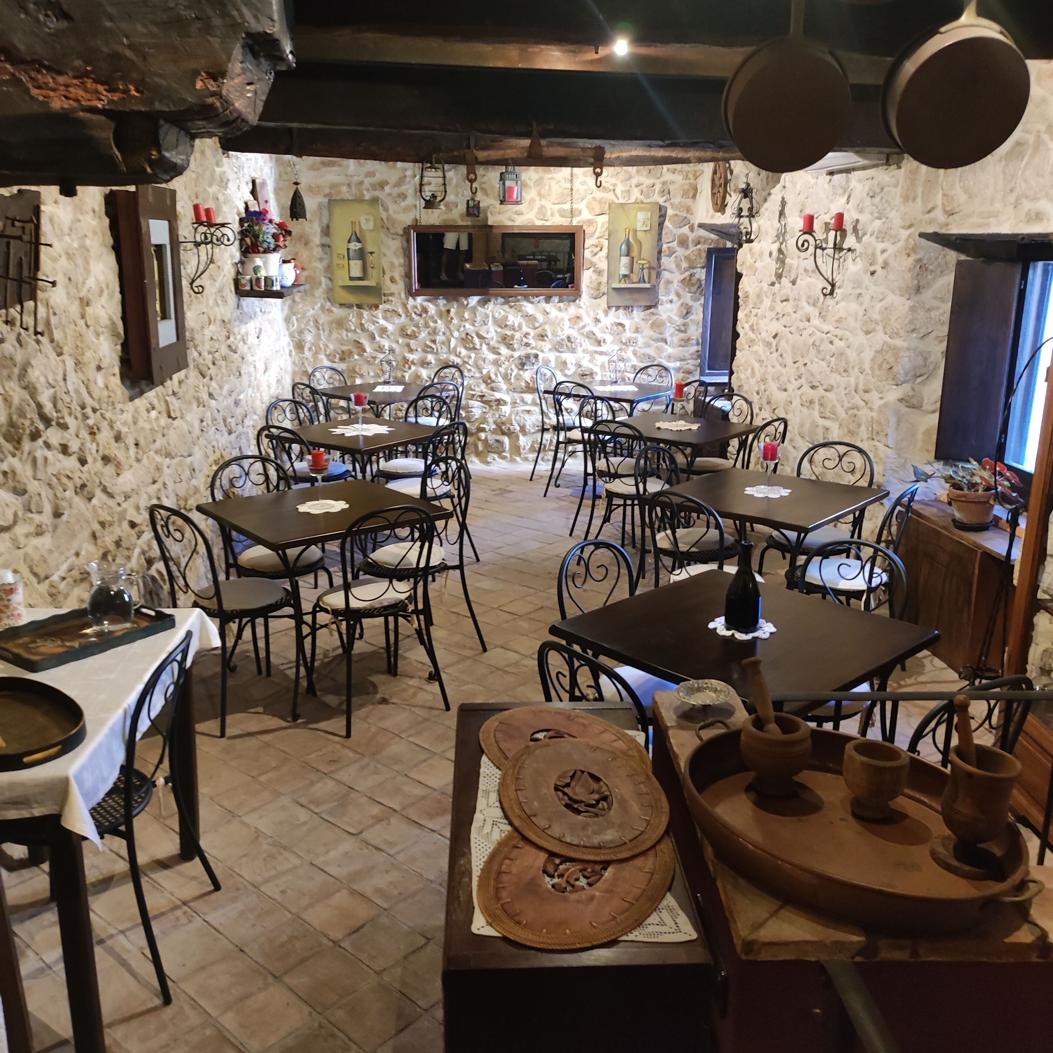 Un comedor rústico con paredes de piedra, mesas de madera y sillas de metal.