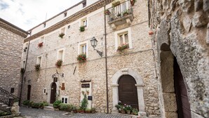 A stone building with multiple windows, a central entrance, and a cobblestone street. - Nena' al Borgo Castello (Pico)