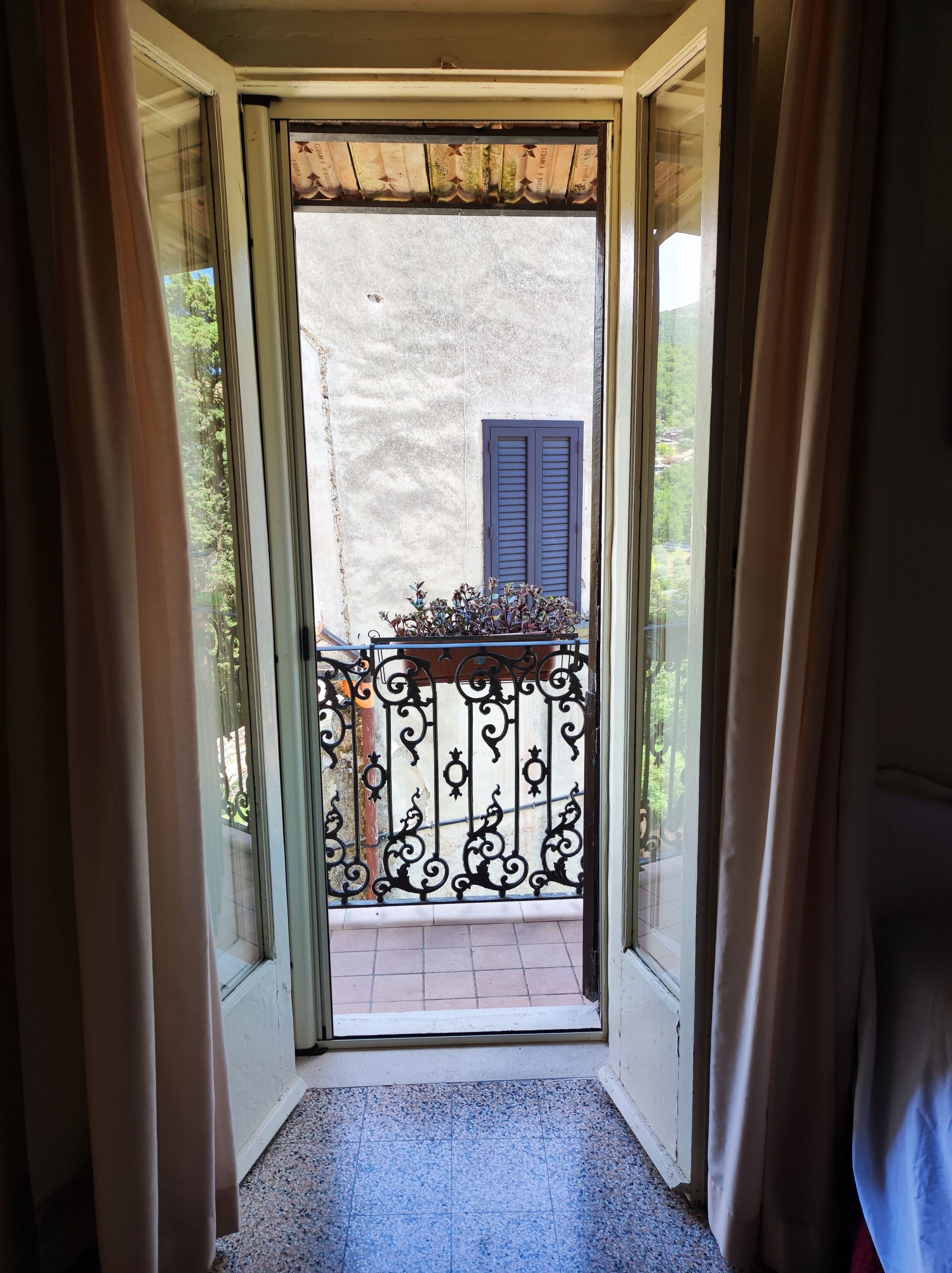 Ein schmaler Ausgang zu einem Balkon mit Metallgeländer und einem Blumentopf.