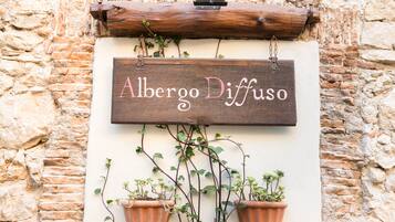 A rustic wooden sign with the name "Alberto Diffuso" hanging on a stone wall.