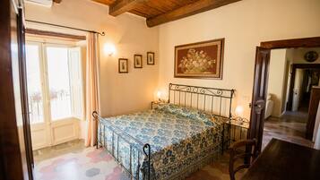 Un dormitorio con cama, techo de madera, una puerta y una pared decorada con cuadros.