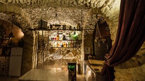 A bar with a rustic stone ceiling and shelves stocked with bottles. - Nena' al Borgo Castello (Pico)