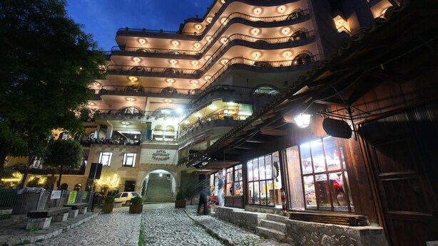 Un edificio de varios pisos con balcones y un patio empedrado.