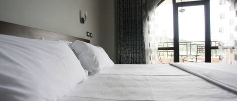 A neatly made bed with white linens in a hotel room.