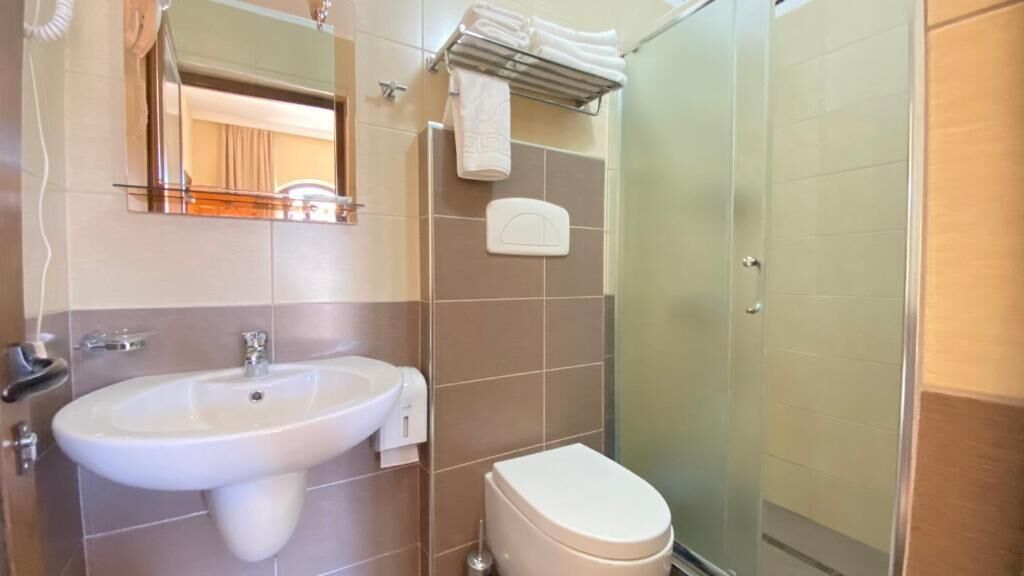 A bathroom with a sink, toilet, and a glass shower enclosure.