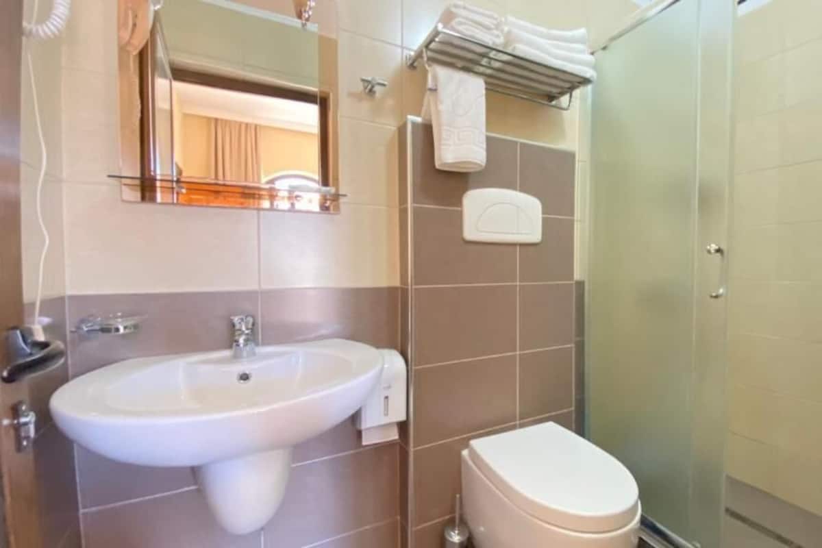 A bathroom with a sink, toilet, and a glass shower enclosure.