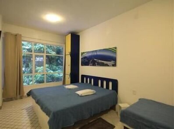 A bedroom with two beds, a window with curtains, and a wall-mounted picture.