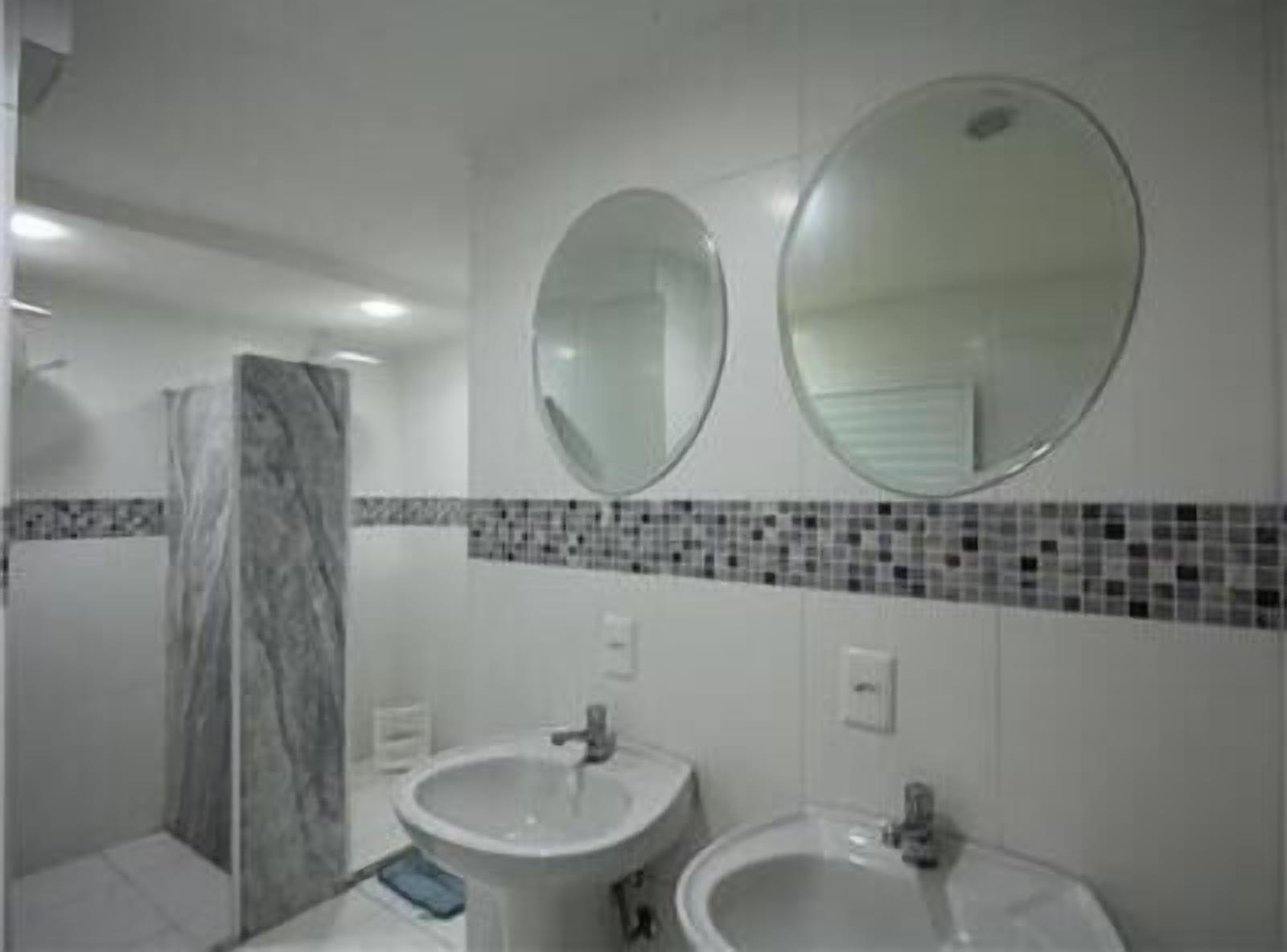 Un baño con dos lavamanos, una ducha y dos espejos.