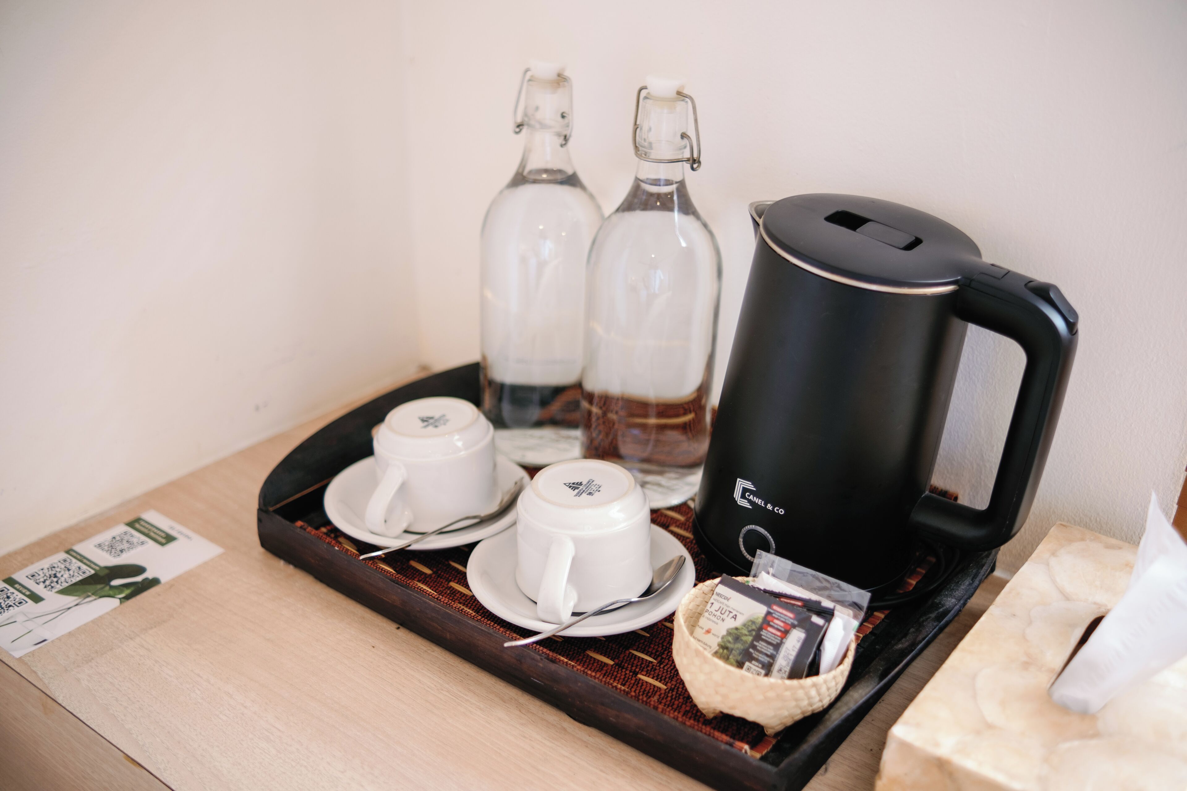 A tray with coffee cups, a coffee pot, and a small basket of tea bags.
