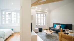 A modern living room with a sofa, coffee table, and a television. - D'Autor Apartments (Porto)