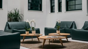 A modern lobby with green leather sofas, wooden coffee tables, and potted orchids. - D'Autor Apartments (Porto)