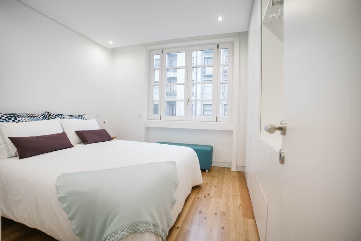 A bedroom with a bed, a window, and a door.