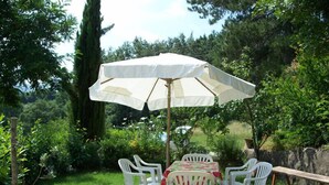 A patio with a table and chairs, an umbrella, and a stone wall. - Agriturismo Santa Caterina (Castelnuovo di Val di Cecina)
