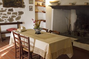 Un comedor con una mesa dispuesta para cuatro, una pared de piedra y una chimenea.