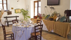 A dining area with a table set for a meal, chairs, a bench, and a television on the wall. - Agriturismo Santa Caterina (Castelnuovo di Val di Cecina)