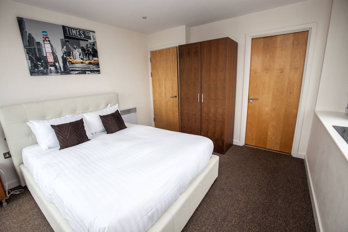 A hotel room with a large bed, a wardrobe, and a desk.