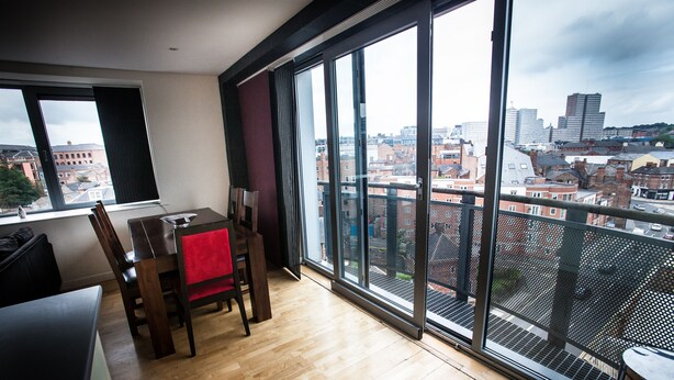 A modern room with a large window, a dining table, and a view of the cityscape. - Cranbrook House Serviced Apartments (Nottingham)