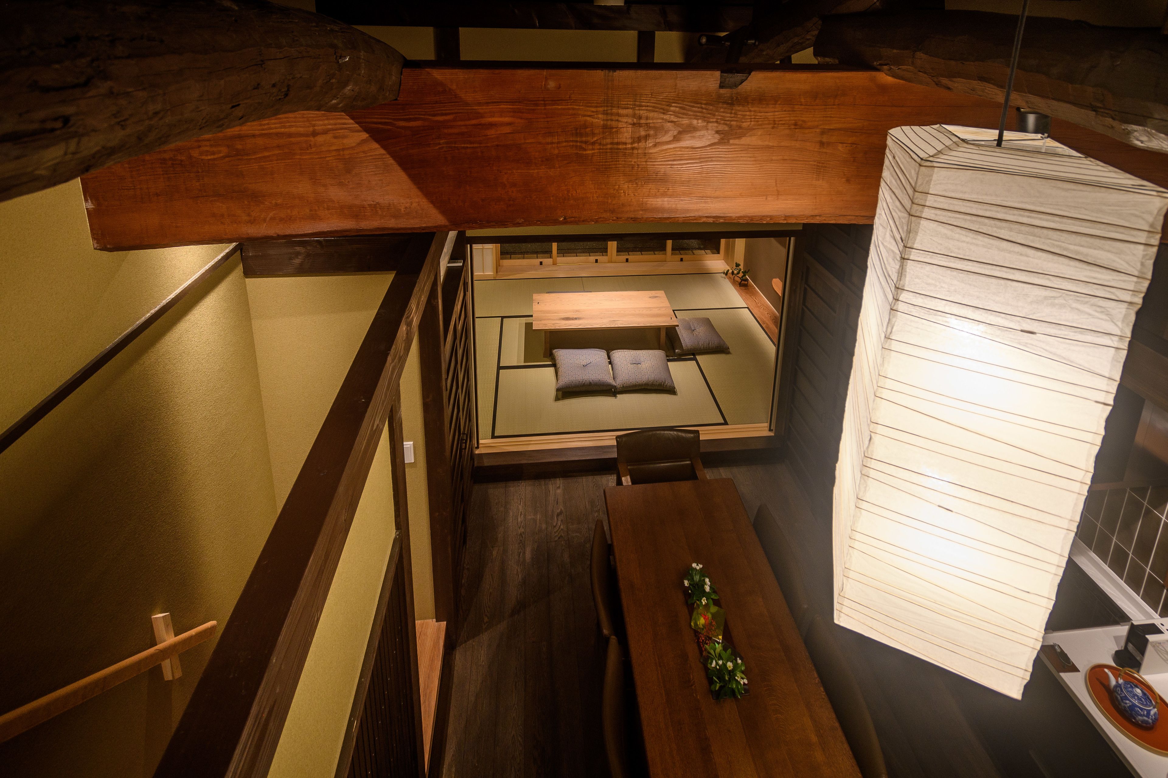 Habitació japonesa tradicional amb fons de tatami, taula de fusta baixa i llit plegable.