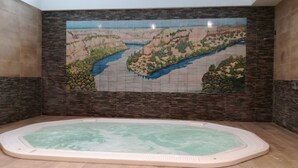 A spa room with a large bathtub and a mural of a river landscape on the wall. - Hotel Rural Puente del Duraton (Sepulveda)