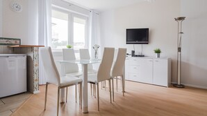 Una cocina moderna con comedor, armarios blancos, televisor de pantalla plana y un ventanal grande.