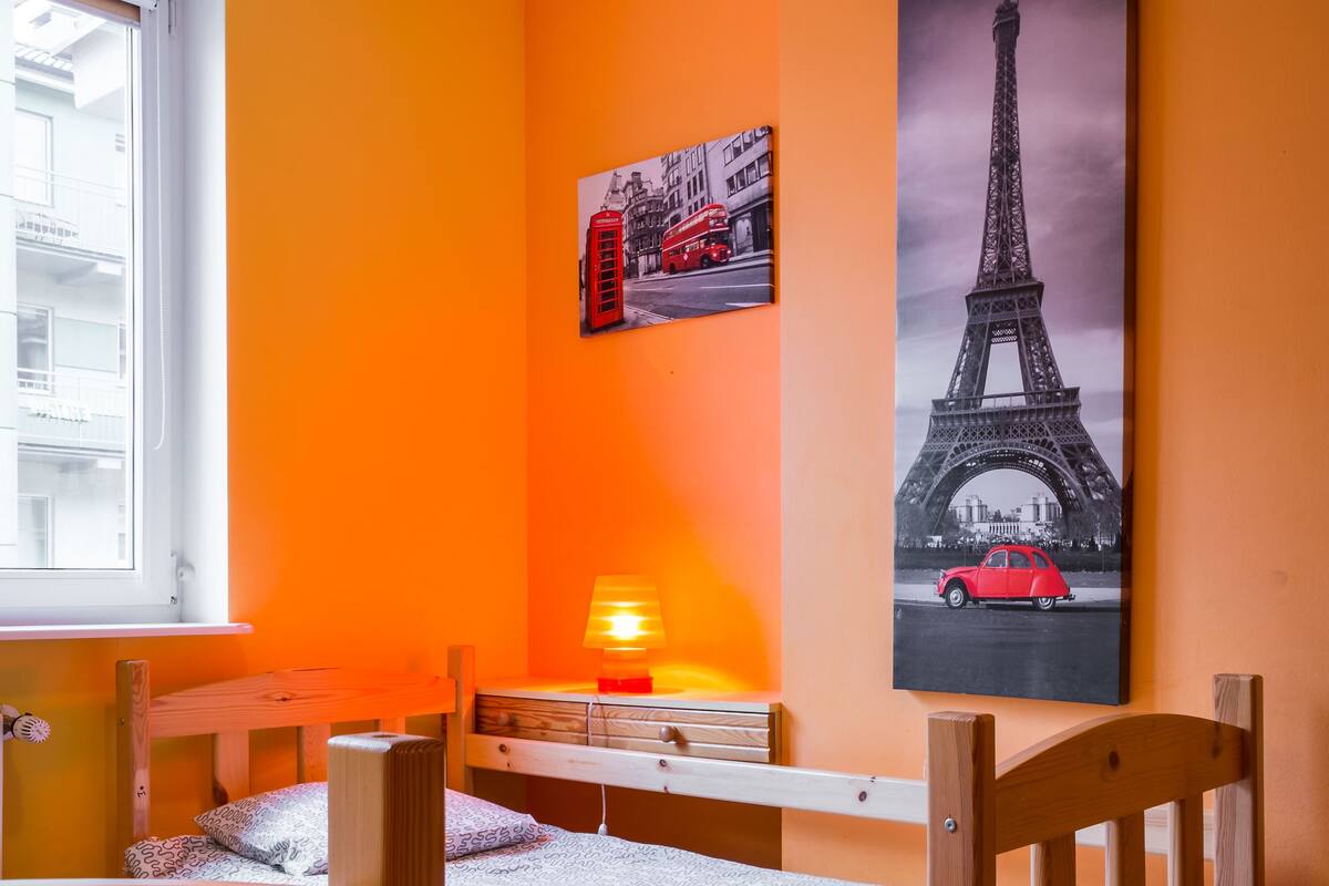 A room with two bunk beds, a desk with a lamp, and a large Eiffel Tower poster on the wall.
