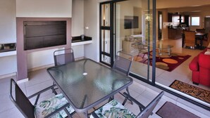 Una sala de estar moderna con un separador de vidrio, un comedor con mesa de vidrio y una cocina al fondo.