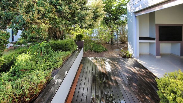 Una terraza de madera que conduce a un edificio moderno con garaje.