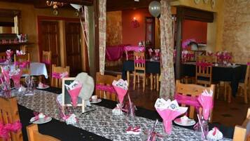 Zona pranzo con tavoli apparecchiati per una festa, decorata con elementi rosa e bianchi.