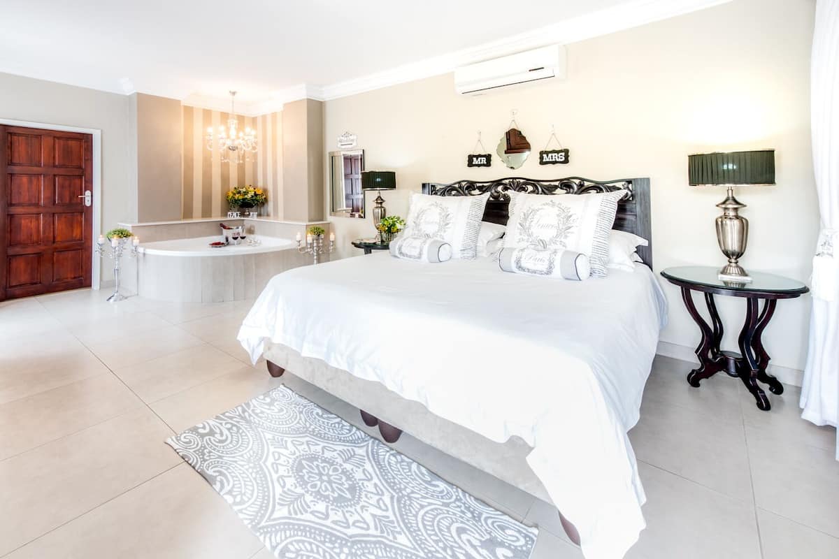 A spacious bedroom with a large bed, a separate bathroom, and a chandelier.