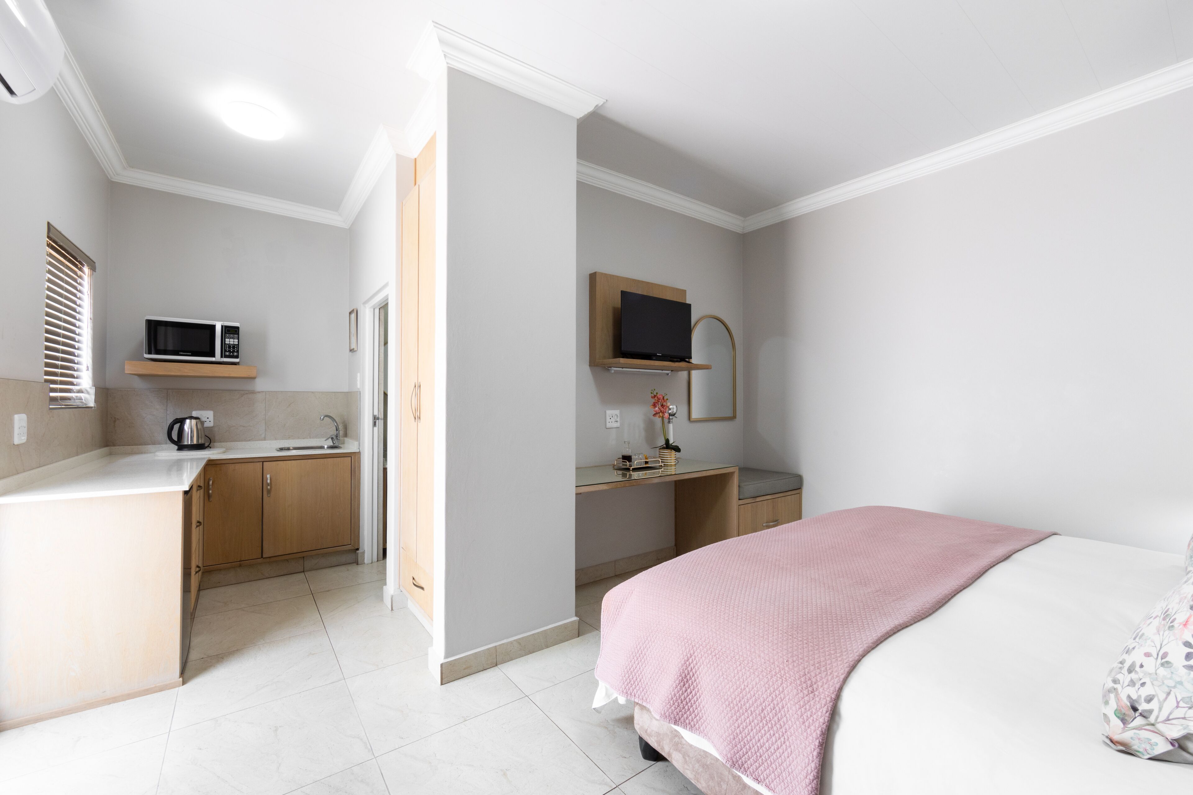 Une pièce compacte comprenant un coin cuisine, un lit et un petit espace bureau.