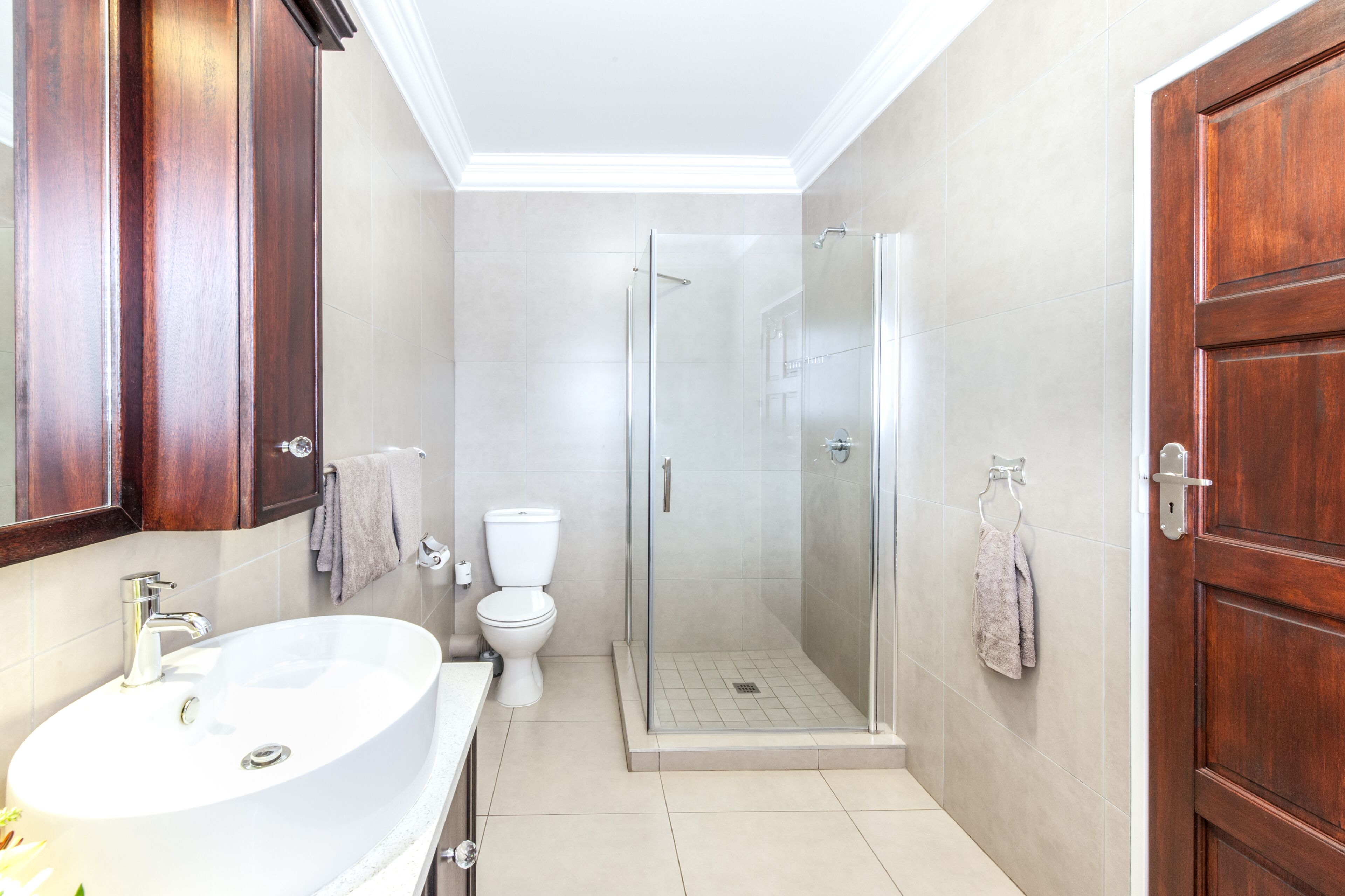 A bathroom with a large white sink, a toilet, and a glass-enclosed shower.
