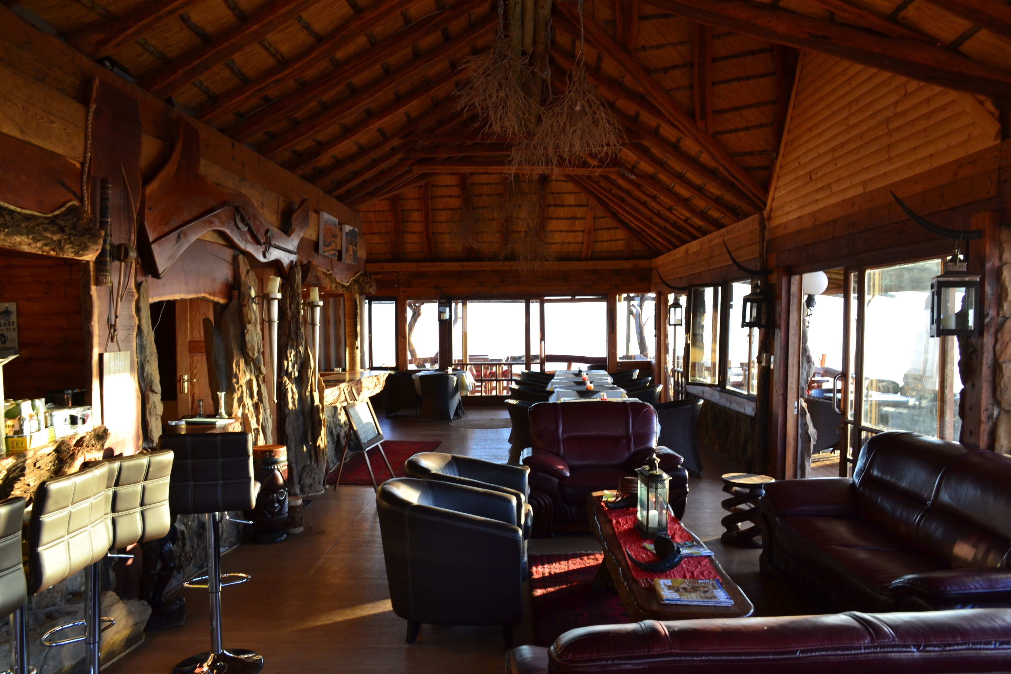 Un interior rústico con vigas de madera, asientos de cuero y un ventanal con vistas.