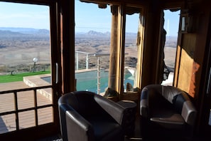 Una habitación con dos sillones de cuero, vista a un paisaje montañoso y una piscina visible a través de la ventana.