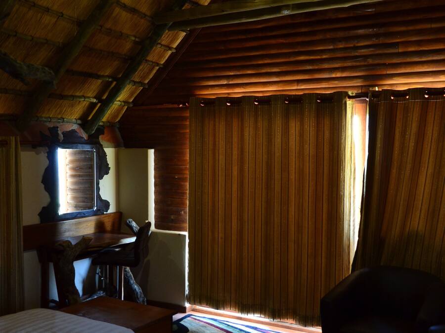 Een kamer met twee bedden, een houten plafond, een kroonluchter, een bureau en een raam met gordijnen.