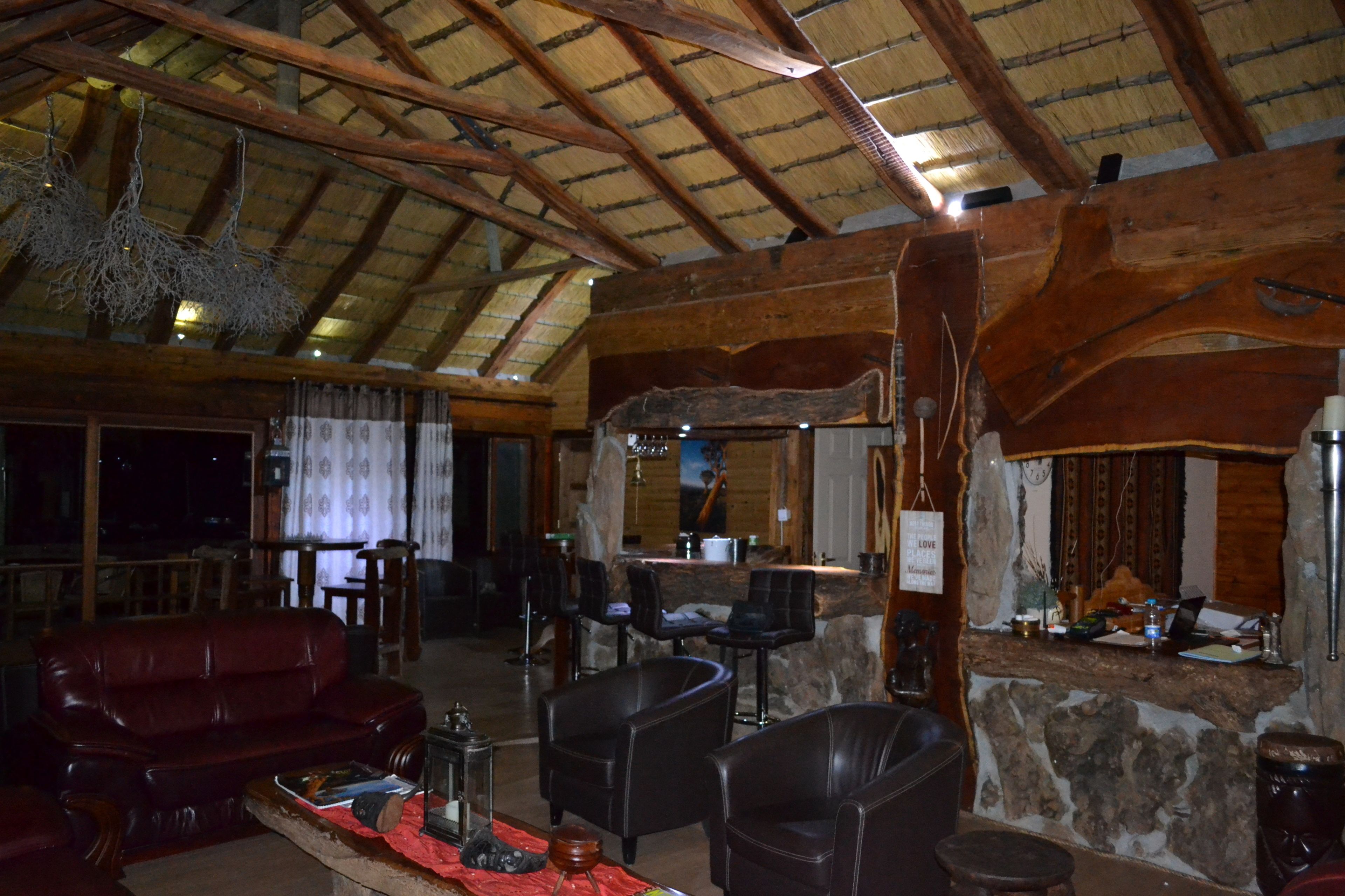 Un interno rustico con soffitto in legno a volta, pareti in pietra, un divano in pelle e un angolo bar.
