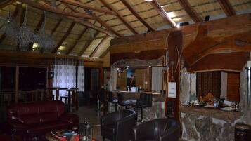 Un interno rustico con soffitto in legno a volta, pareti in pietra, un divano in pelle e un angolo bar.