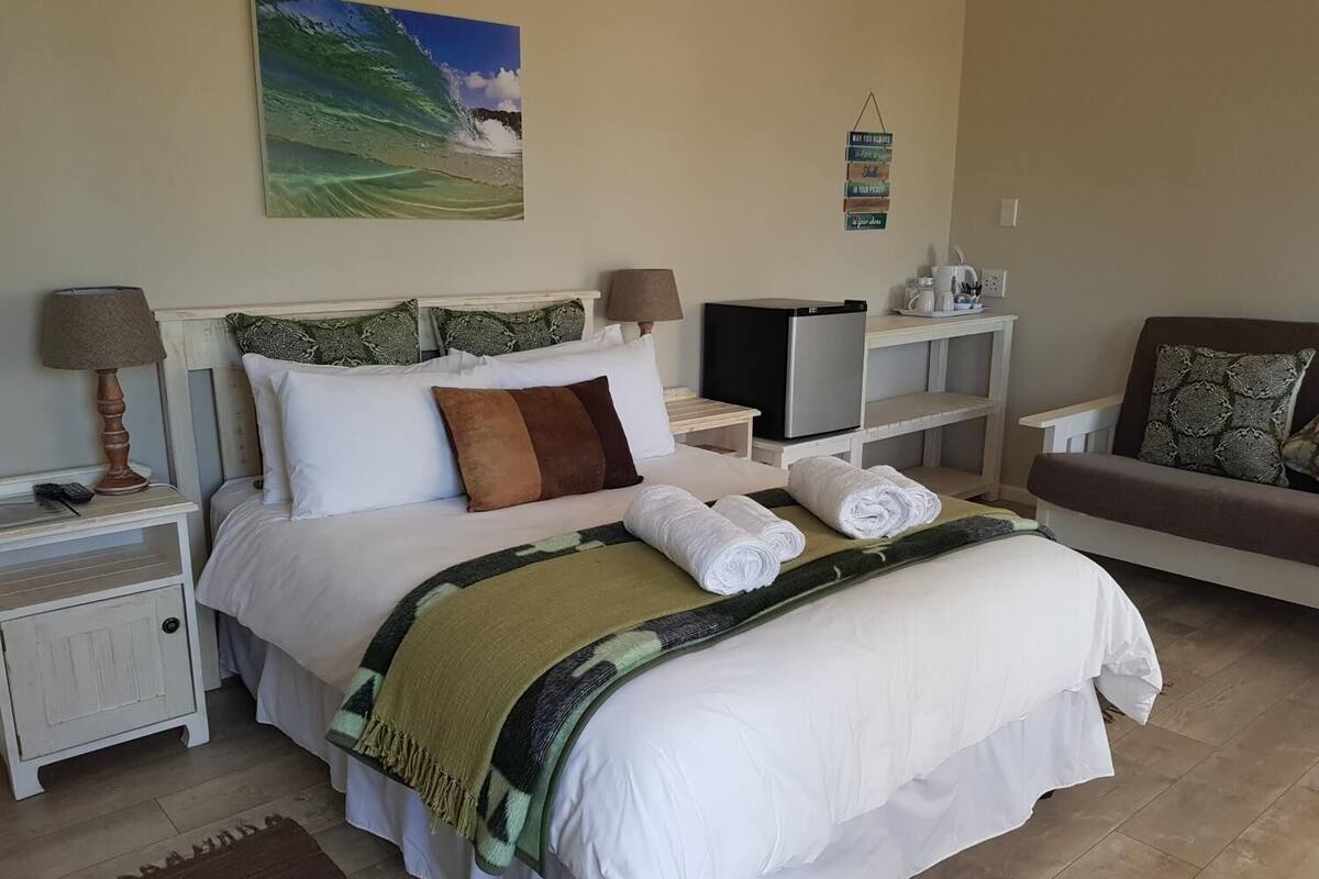 A neatly arranged bedroom with a bed, bedside tables, a TV, a coffee maker, and a sofa.