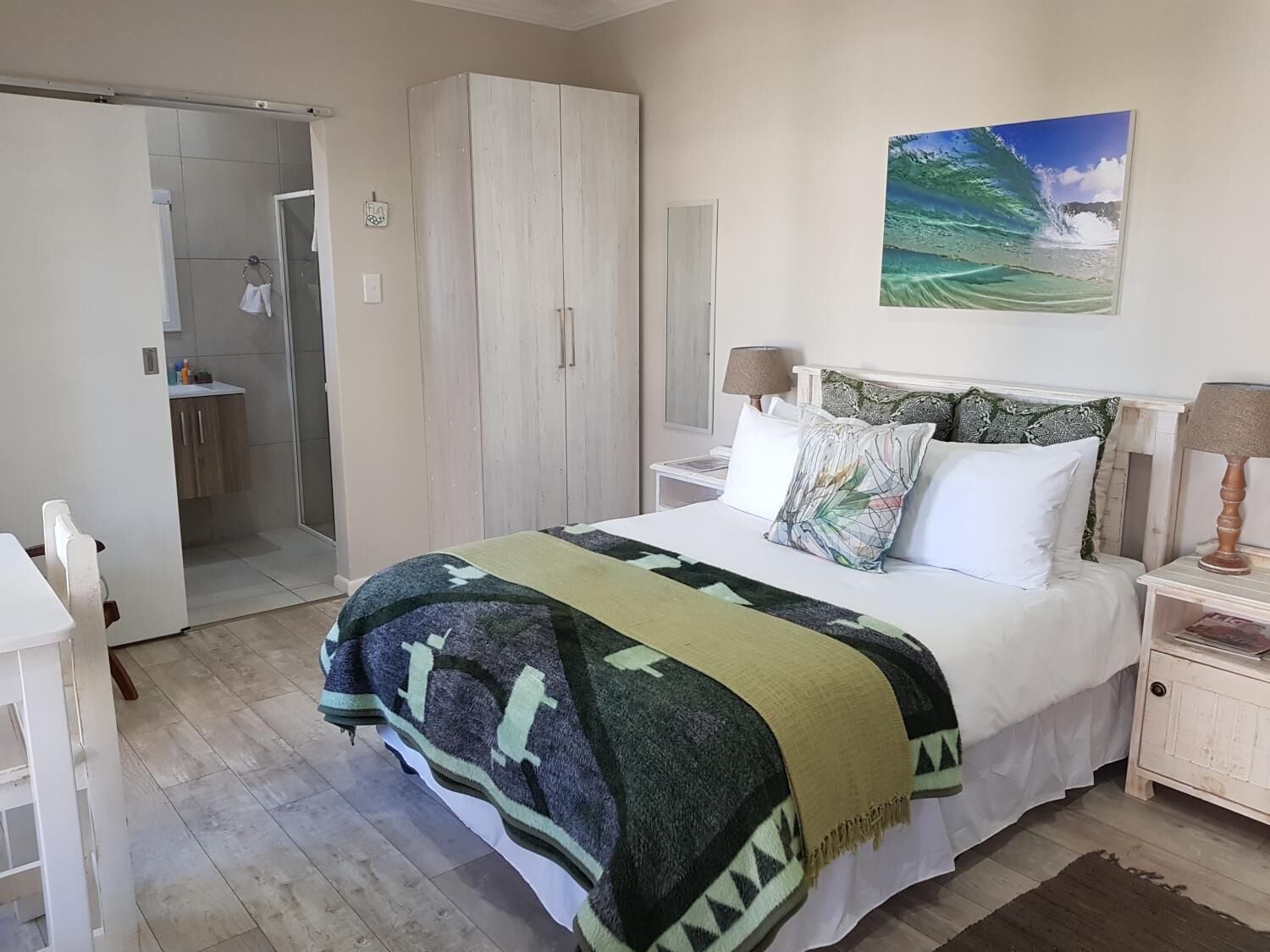 Un dormitorio con cama, mesita de noche, armario y baño visible a través de una puerta abierta.