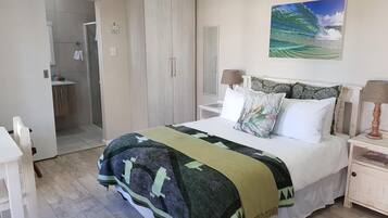 Un dormitorio con cama, mesita de noche, armario y baño visible a través de una puerta abierta.