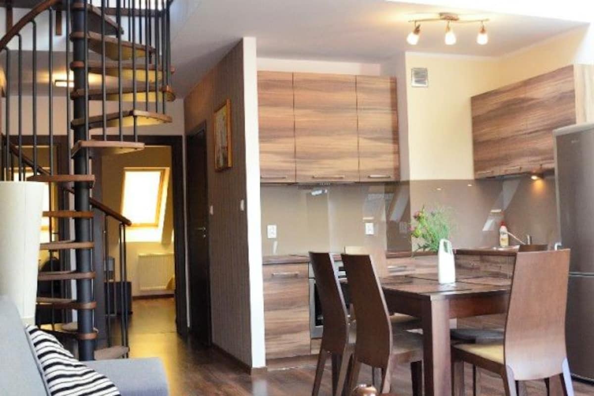 A spacious loft with a mezzanine, a staircase, a dining area, and a kitchen.