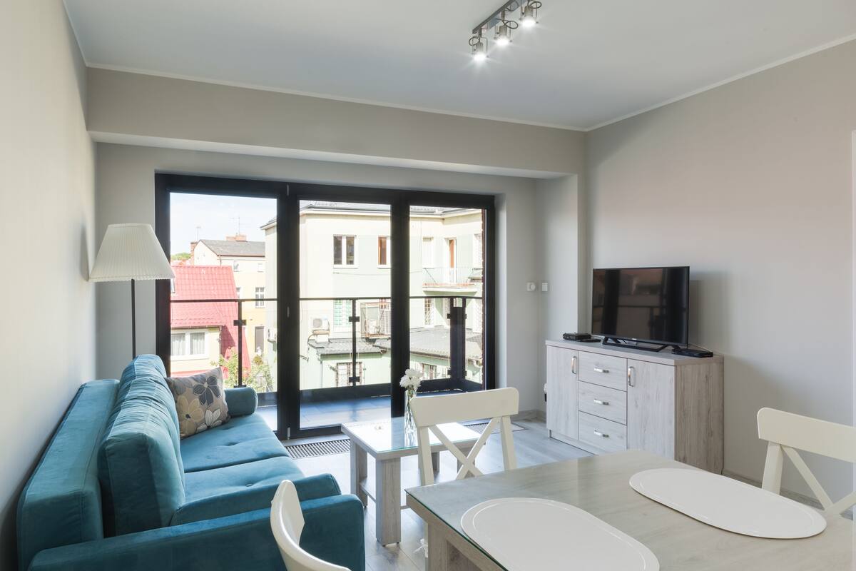 A modern living room with a sofa, a dining table, and a TV.