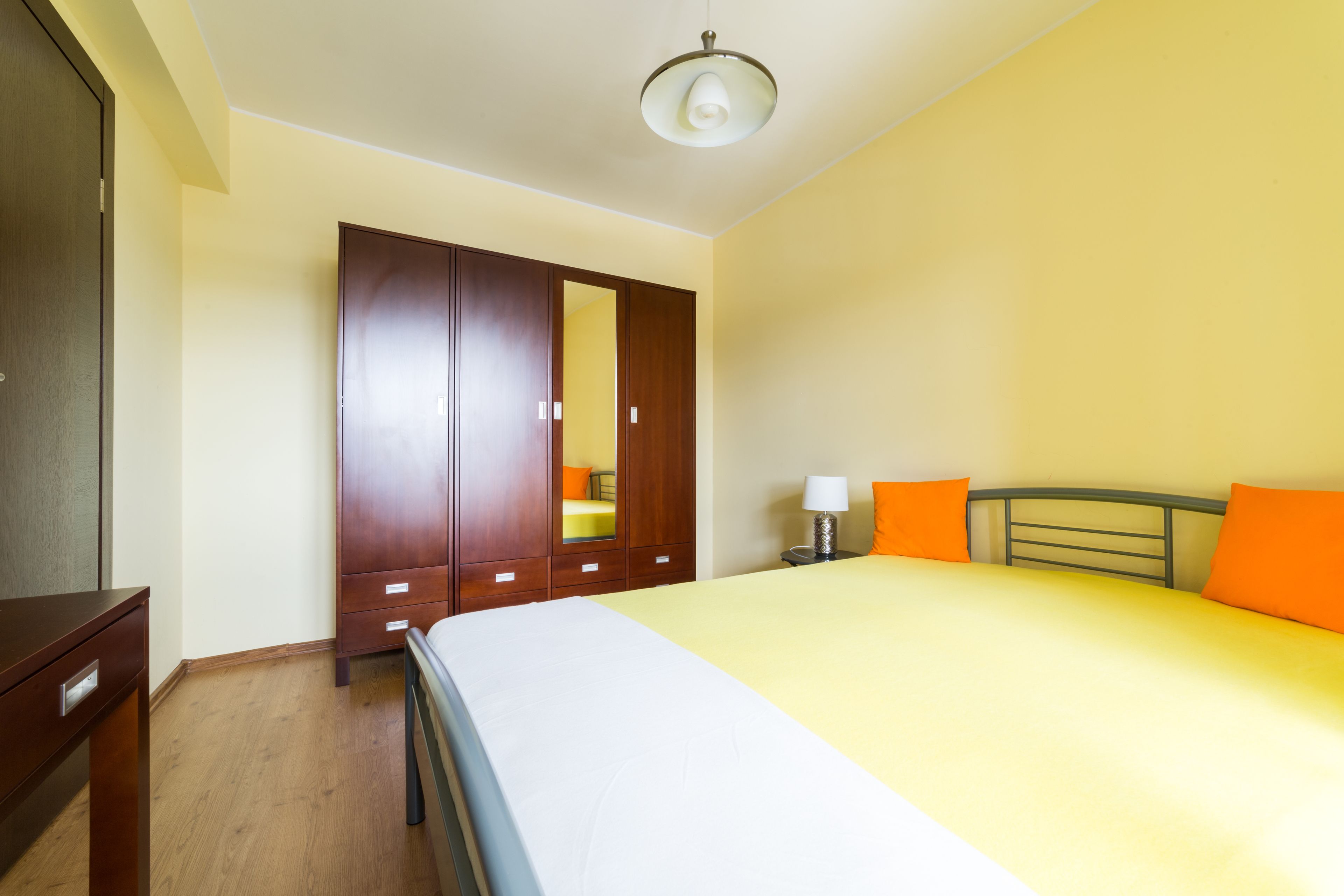 Una camera da letto con un letto, un armadio, un comodino e una lampada.