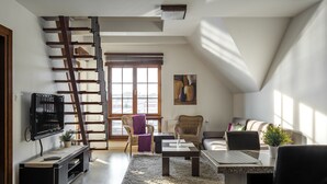Una sala de estar moderna con una escalera de madera, un televisor de pantalla plana, una mesa de centro y un sofá.