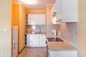 Une cuisine de taille réduite avec des meubles blancs, un évier, une cuisinière et une machine à café.