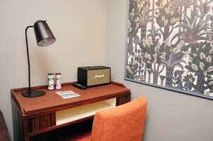 Una scrivania di legno con una lampada, una radio d'epoca e due barattoli di caffè.